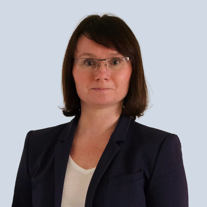 Adriane Sok Frau Sok mit Brille, kurzen braunen Haaren und dunklem Blazer vor einem hellen Hintergrund.